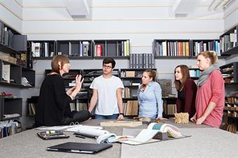 The picture shows a professor and a group of students at the warehouse of the faculty of architecture.